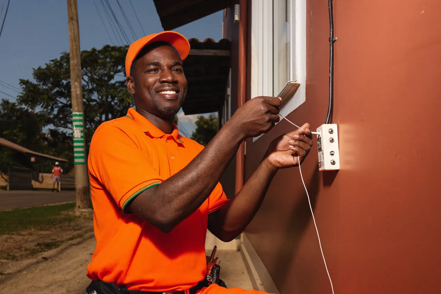 Técnico da HNET instalando o cabo de fibra óptica na parede de uma casa